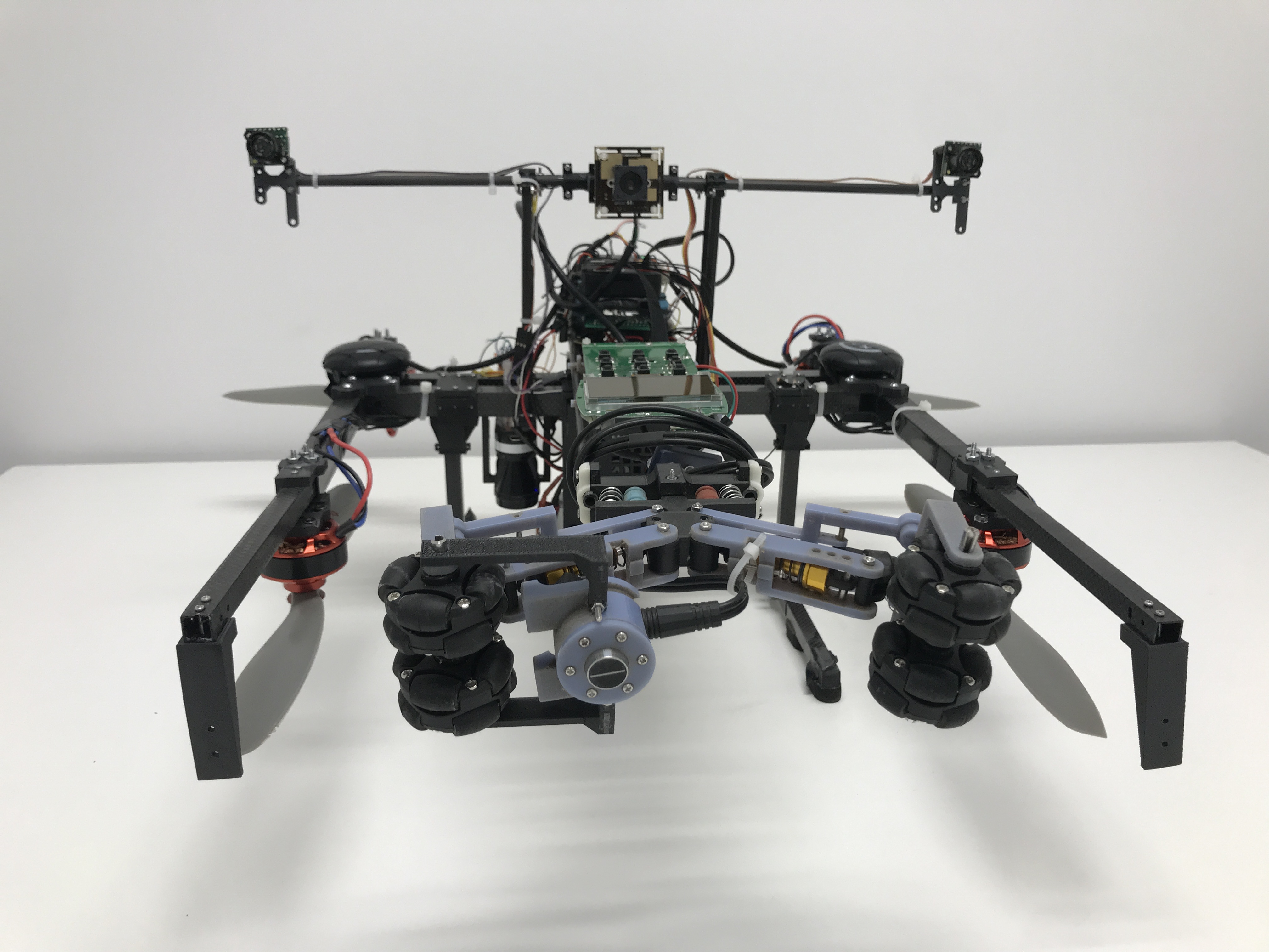 Close-up of an early robotics drone prototype with mechanical grippers and exposed electronics.