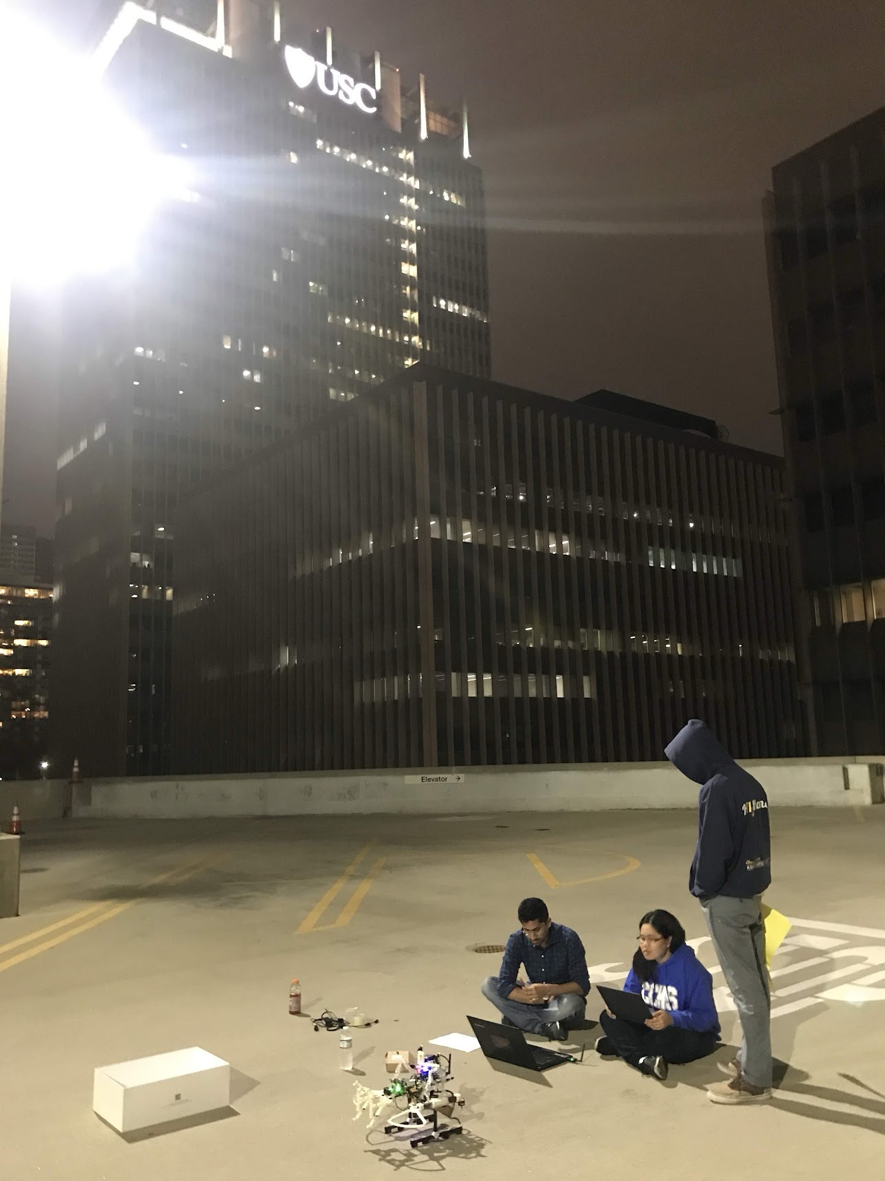 Team testing a robotics prototype outdoors on a rooftop at night.