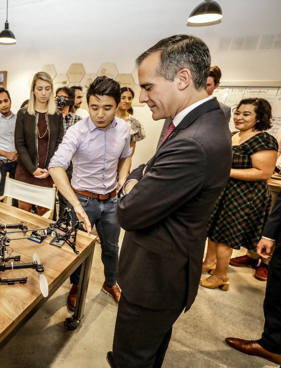 Public demonstration of a robotics prototype with visitors gathered around the workspace.