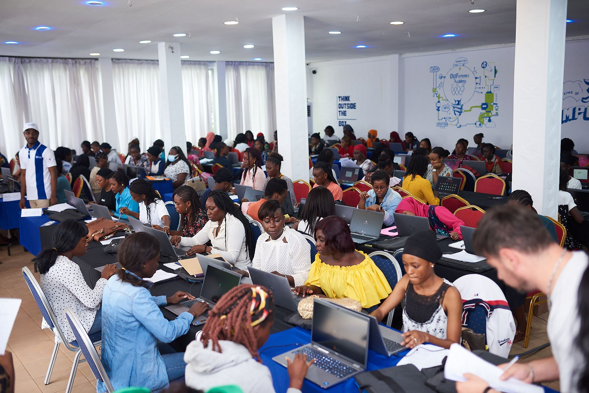 Large room of participants working on laptops during a digital training session.