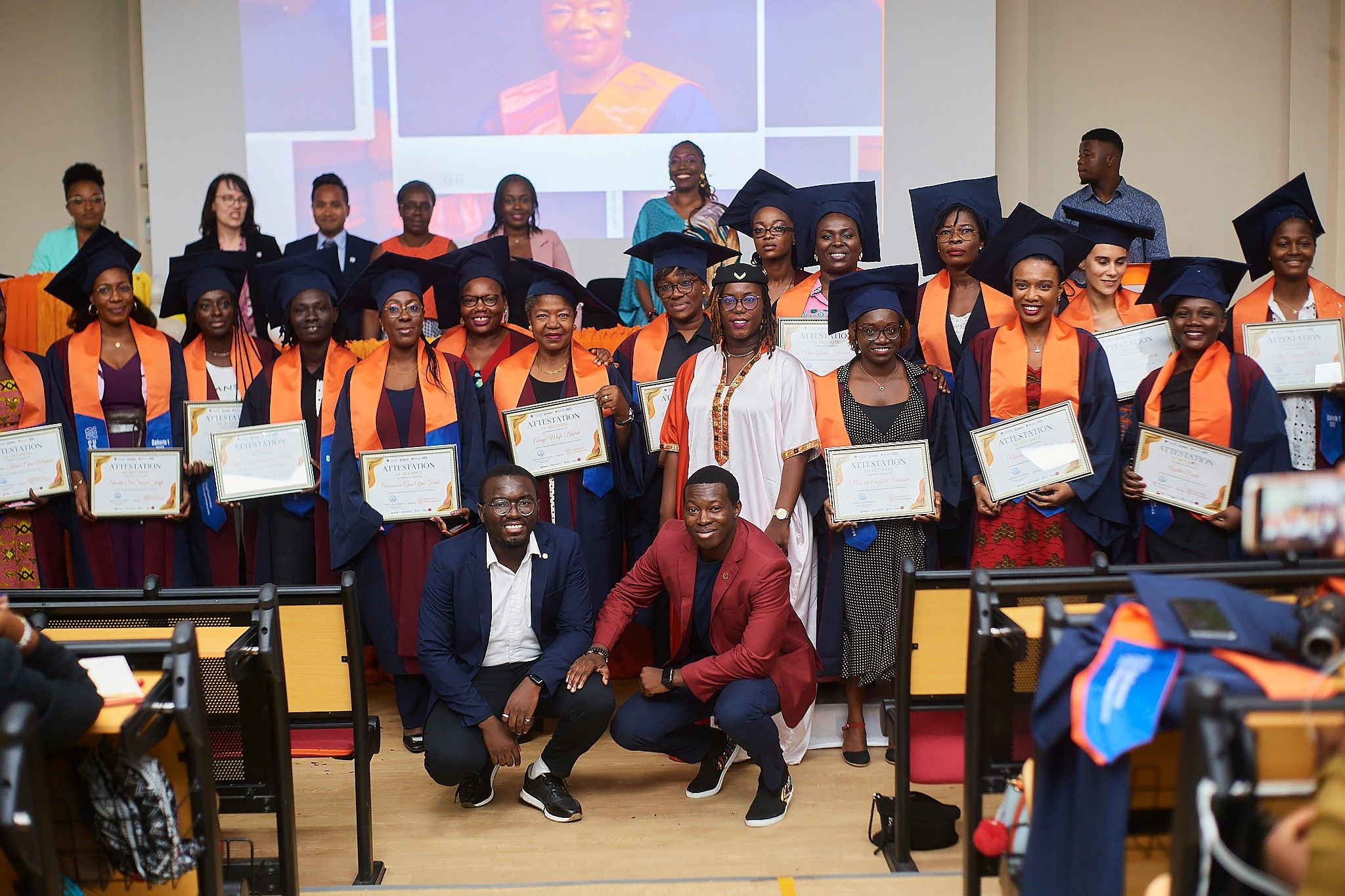 Graduates holding certificates during a large program graduation ceremony.