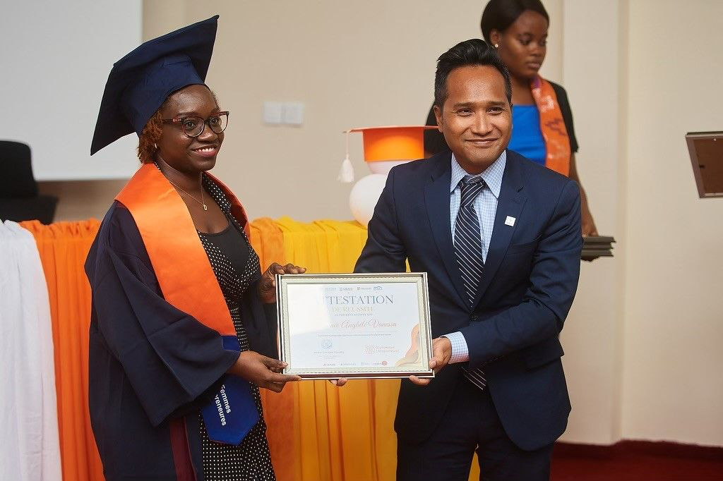 Graduate holding a certificate alongside a program representative.
