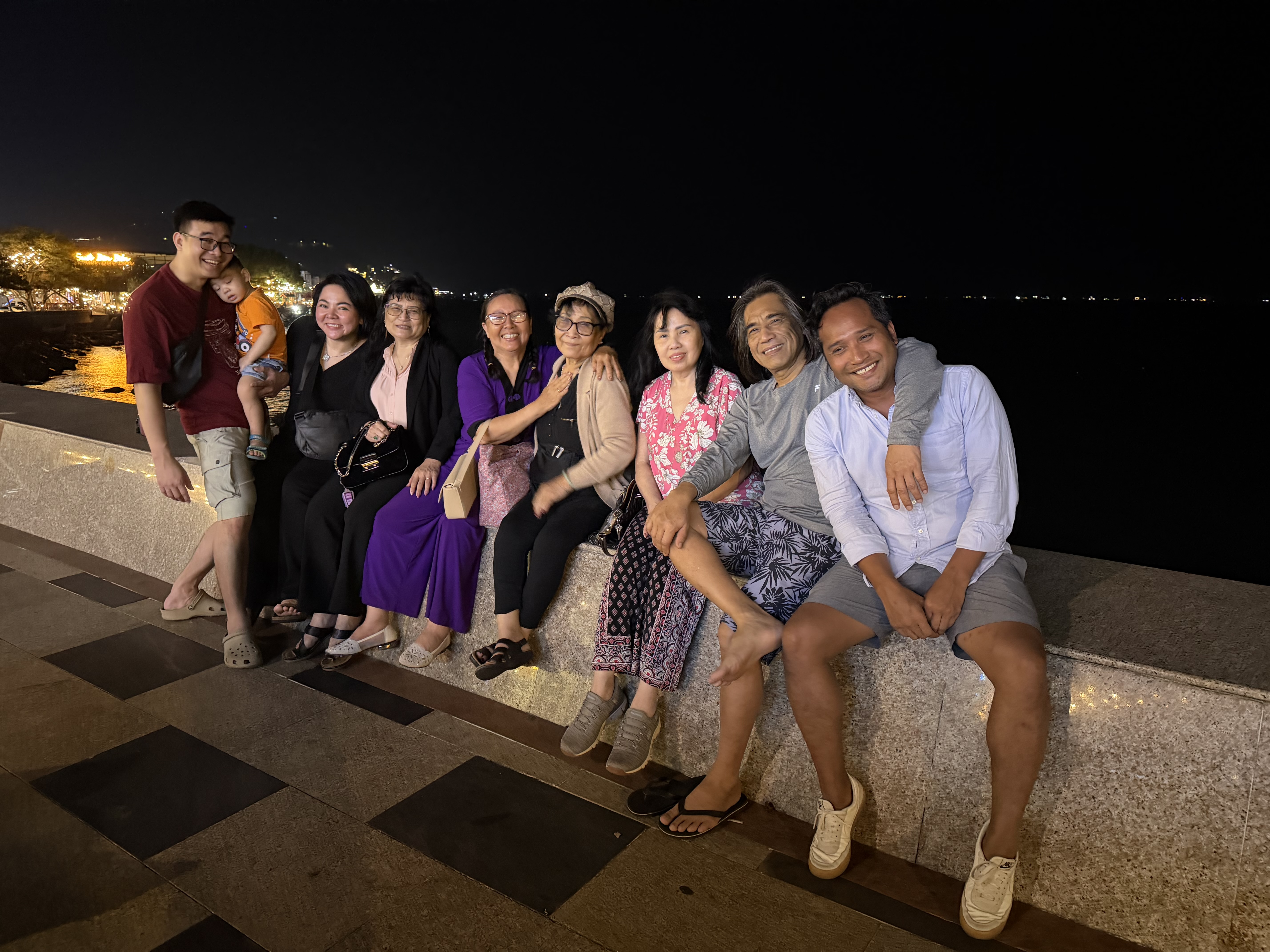 A large group gathered together along a waterfront at night.