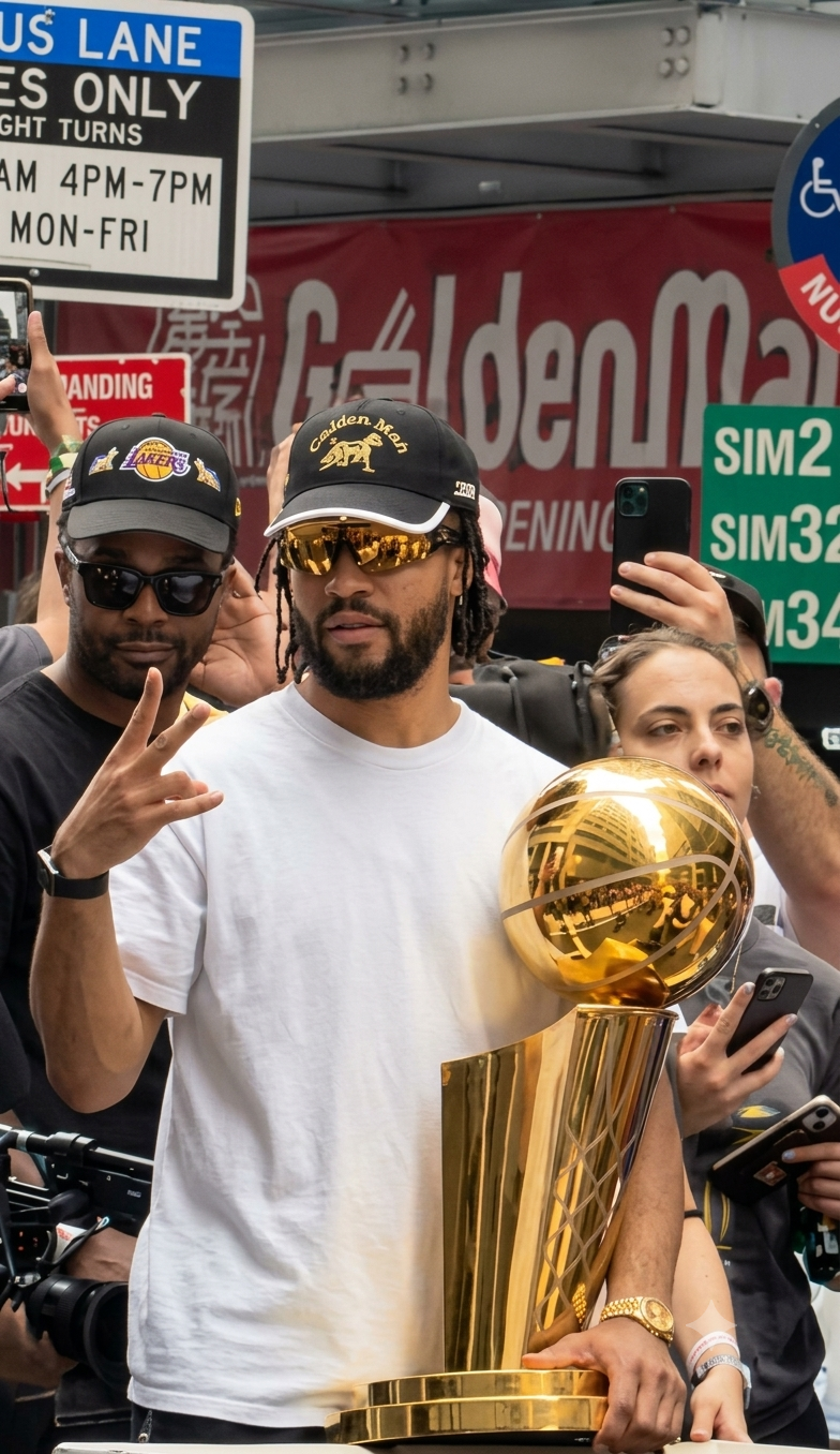 Person standing beside a basketball championship trophy during a street celebration.