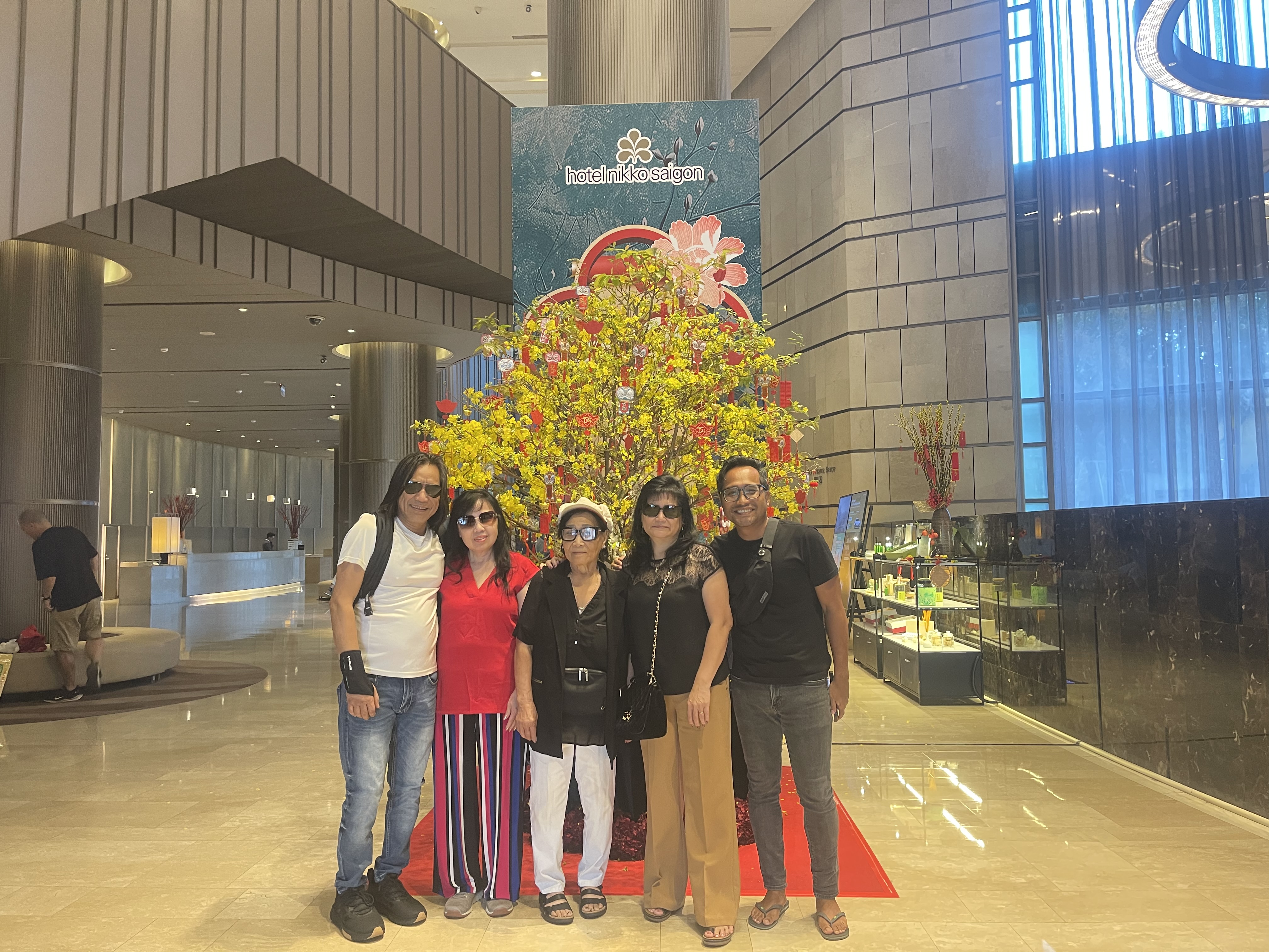 Family posing indoors beside yellow New Year blossoms.