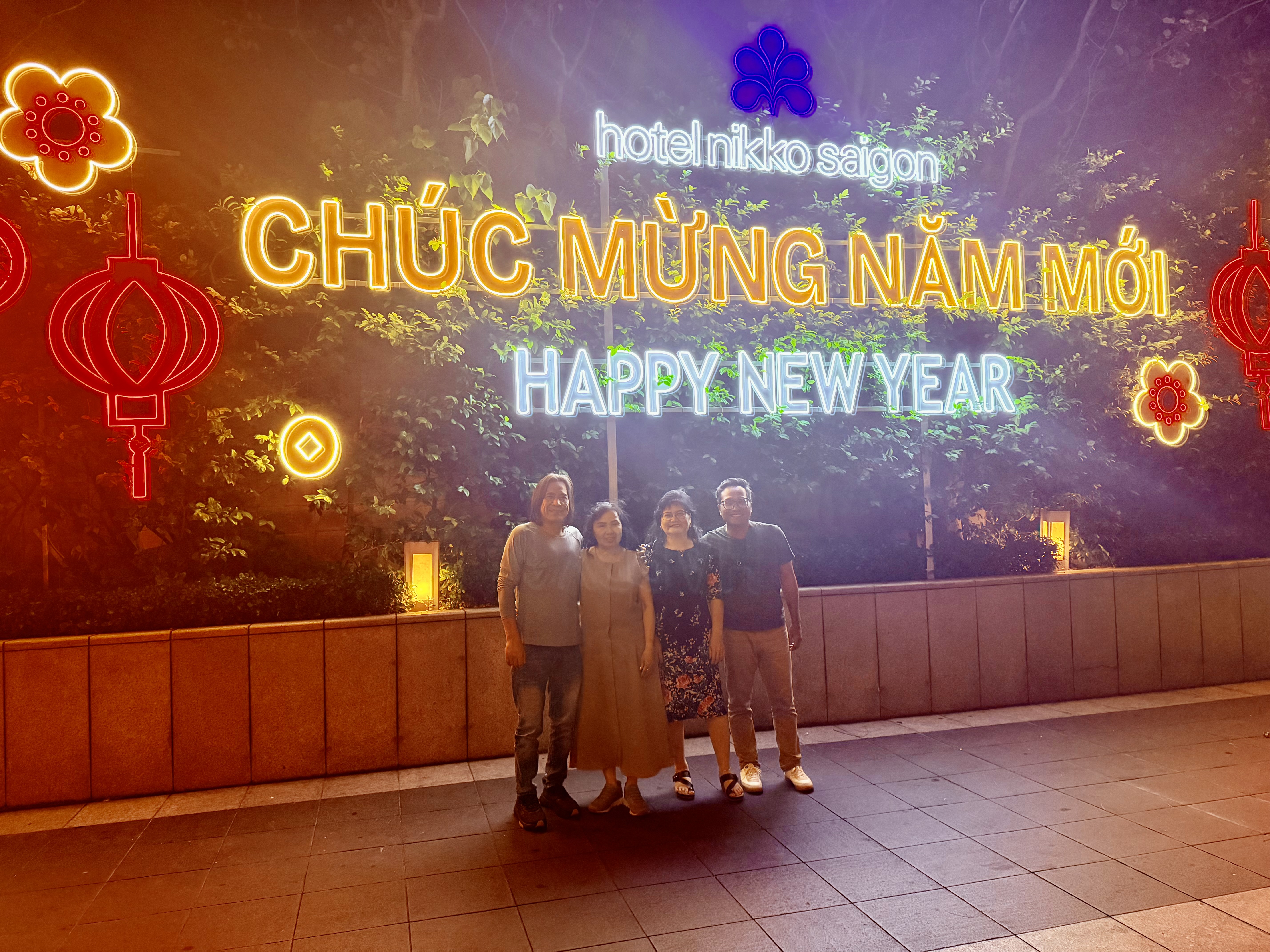 Family group standing beneath illuminated New Year decorations.