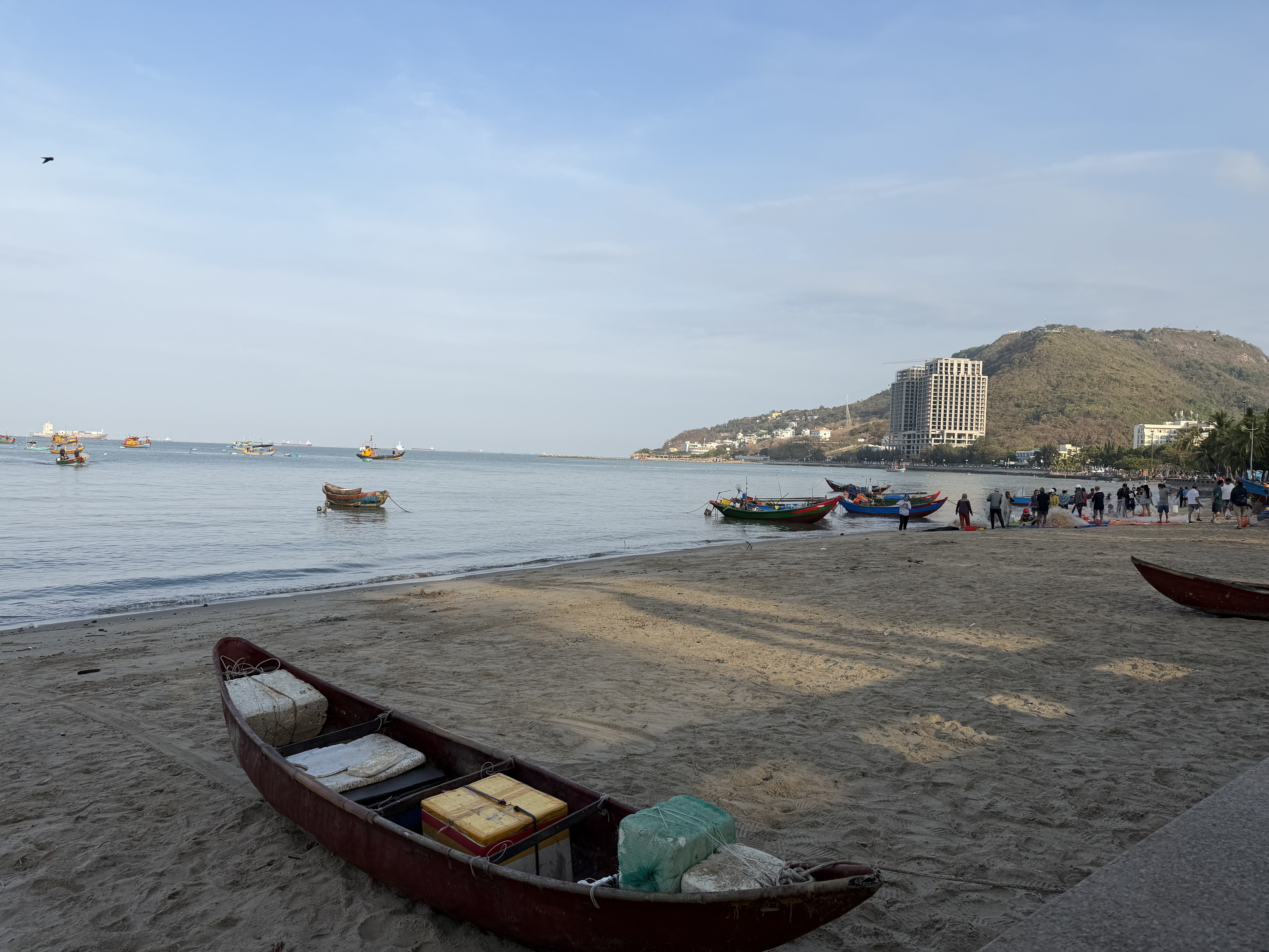 Fishing boats along a beach with hills in the background.
