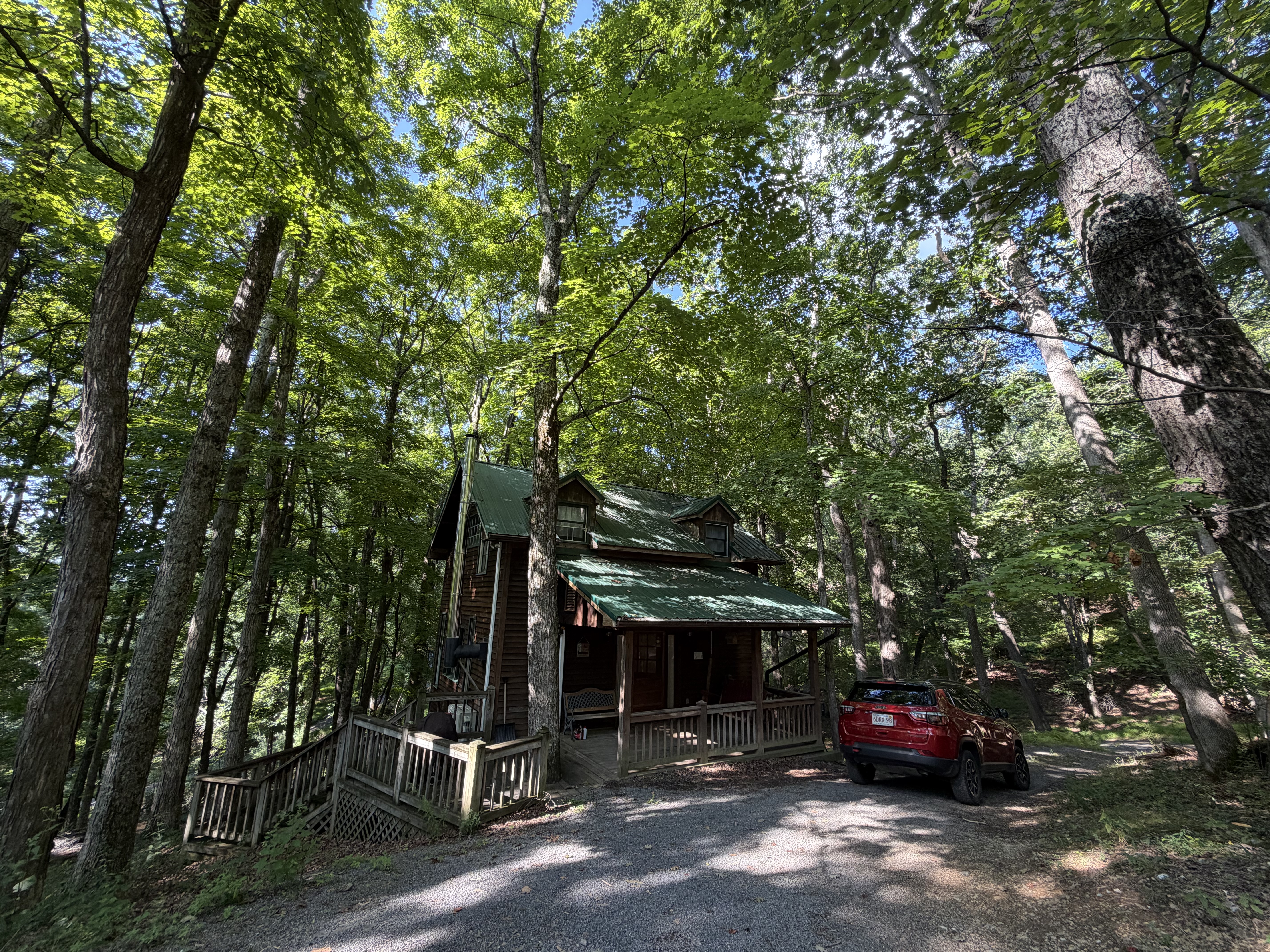 A wooden cabin tucked beneath tall trees in the West Virginia woods.