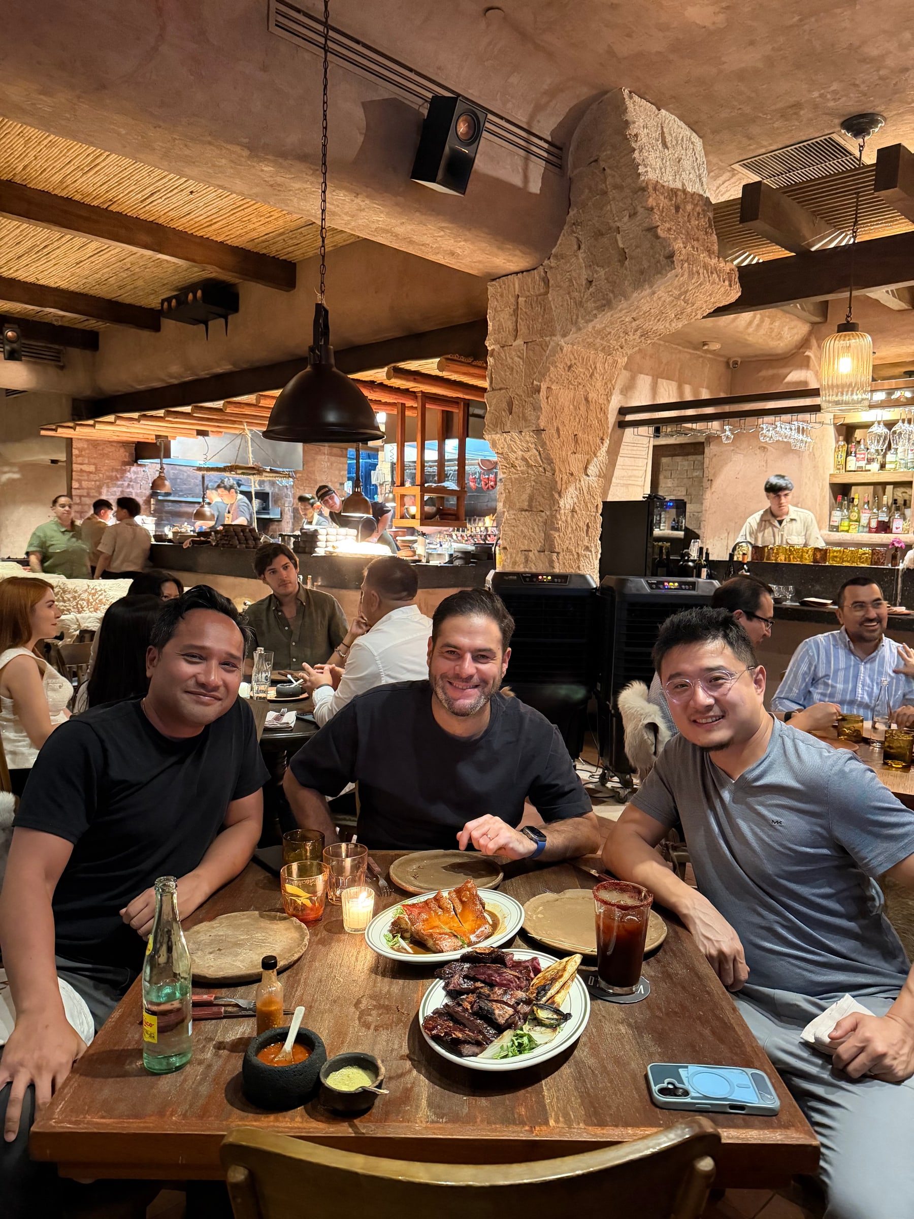 Three friends seated together over dinner in a restaurant.